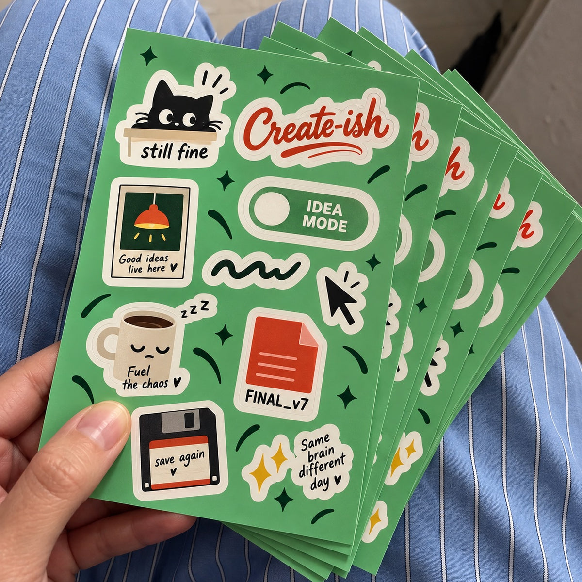 Stack of custom green sticker sheets featuring creative office, coffee, cat, cursor, and motivational designs.