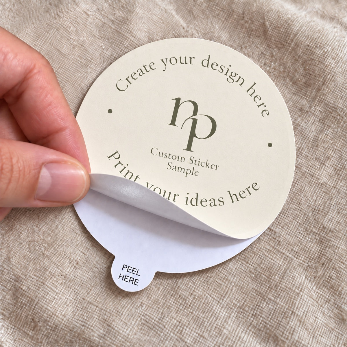 Hand peeling a custom round logo sticker using the easy-peel tab labeled Peel Here.