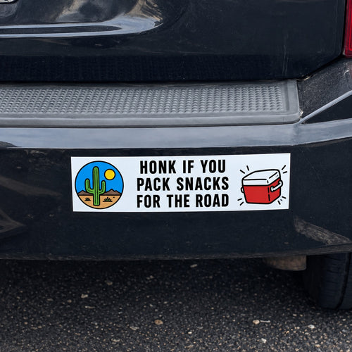 Funny custom bumper sticker reading Honk If You Pack Snacks for the Road on a black SUV.