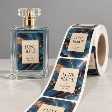 Custom rectangular perfume roll labels with blue marble and gold detailing shown beside a labeled glass bottle.
