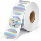 Roll of custom round holographic thank-you stickers with rainbow silver foil and black botanical printing.