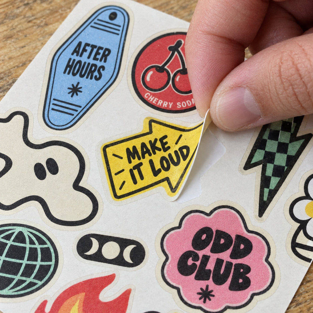 Close-up of a custom vintage sticker sheet as a yellow Make It Loud sticker is peeled from the backing.